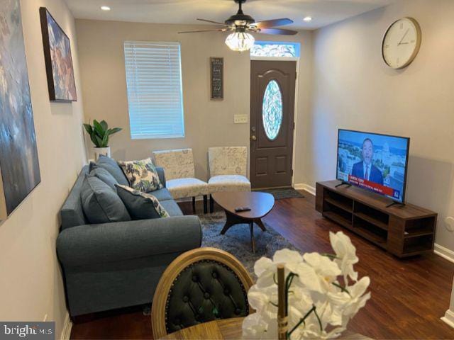 living room with ceiling fan and dark wood-type flooring