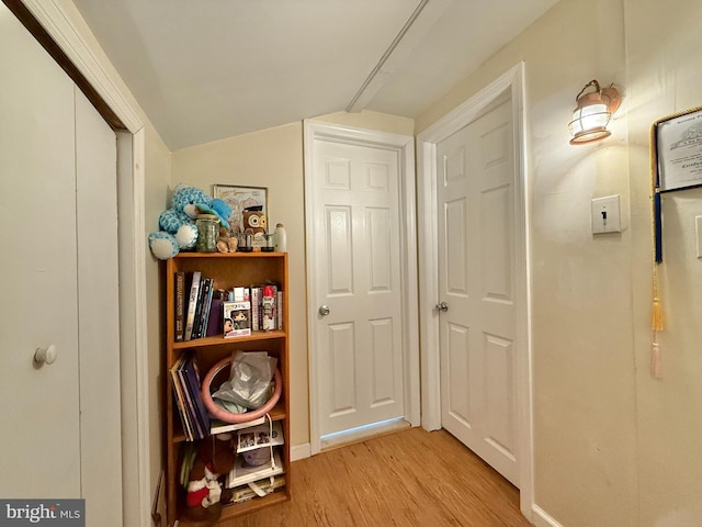 hall with light wood-type flooring and lofted ceiling