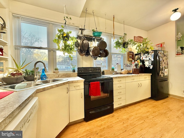 kitchen featuring black appliances, plenty of natural light, sink, and light hardwood / wood-style flooring