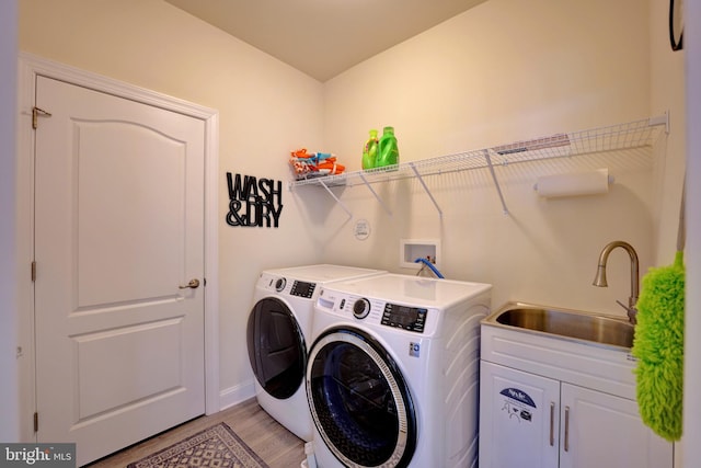 laundry area with cabinets, light hardwood / wood-style floors, washer and clothes dryer, and sink