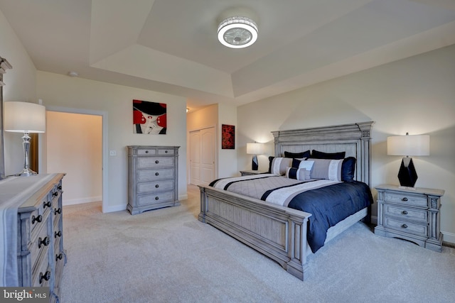 bedroom with a tray ceiling, a closet, and light carpet