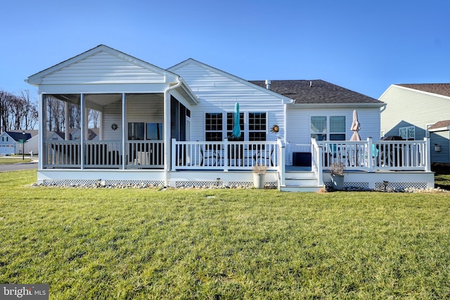 rear view of house with a deck, a sunroom, and a yard