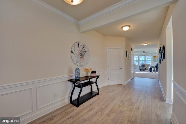 corridor with ornamental molding and light hardwood / wood-style flooring