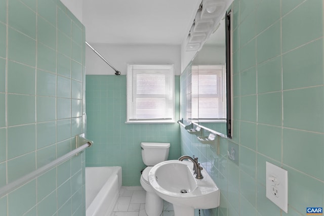 bathroom with a bath, toilet, tile walls, and sink