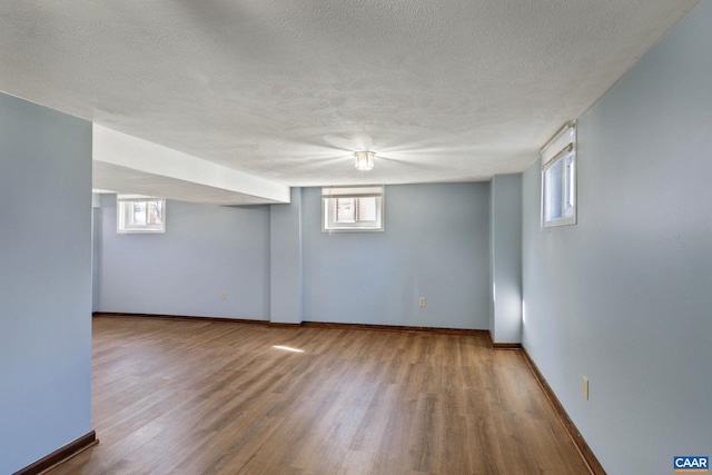 basement with a textured ceiling, hardwood / wood-style flooring, and a healthy amount of sunlight