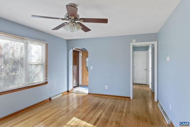 unfurnished room featuring ceiling fan, light hardwood / wood-style floors, and a baseboard heating unit