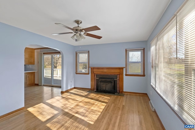 unfurnished living room with ceiling fan, a fireplace, and light hardwood / wood-style flooring