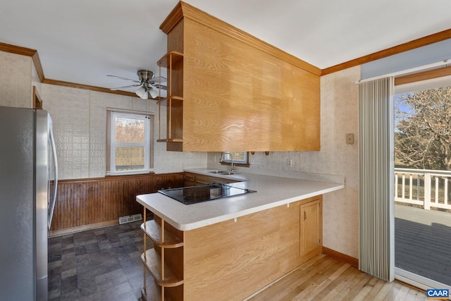 kitchen with dark wood-type flooring, black electric stovetop, sink, kitchen peninsula, and stainless steel refrigerator