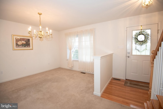 foyer with light hardwood / wood-style floors, an inviting chandelier, and plenty of natural light