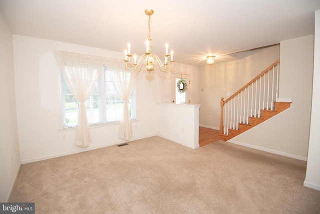 empty room with carpet flooring and an inviting chandelier