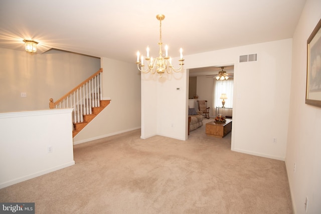 carpeted empty room featuring ceiling fan with notable chandelier