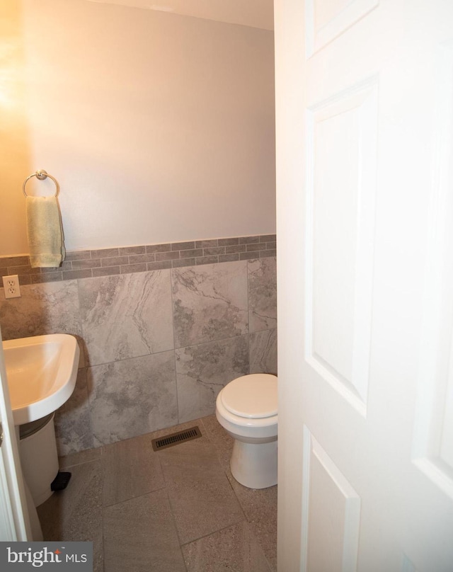 bathroom featuring tile patterned floors, tile walls, and toilet