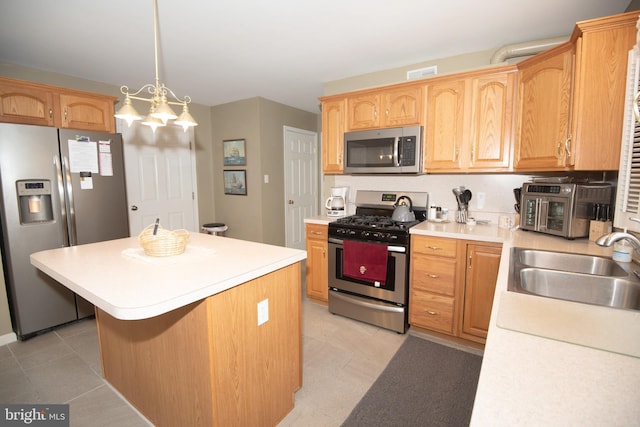 kitchen featuring appliances with stainless steel finishes, sink, decorative light fixtures, a chandelier, and a kitchen island