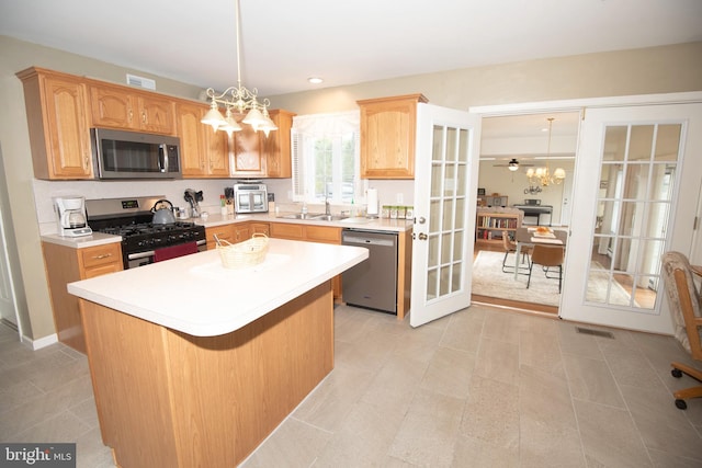 kitchen featuring decorative light fixtures, stainless steel appliances, an inviting chandelier, and a kitchen island