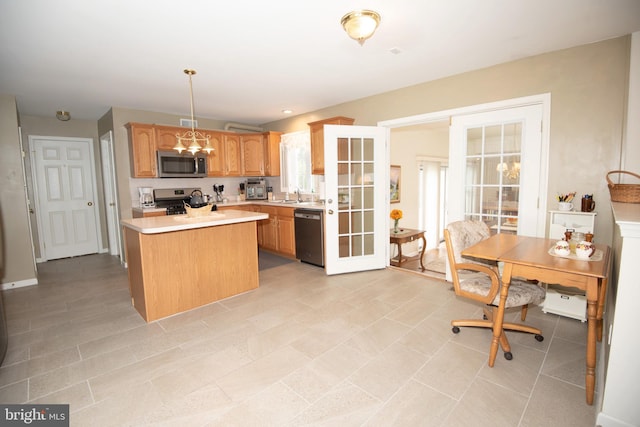 kitchen with french doors, stainless steel appliances, sink, a kitchen island, and hanging light fixtures