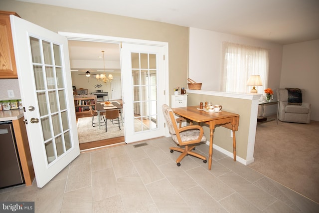 dining space featuring french doors, ceiling fan with notable chandelier, and light colored carpet