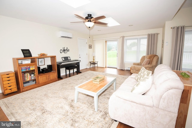 living room featuring a wall mounted AC, hardwood / wood-style flooring, a skylight, and ceiling fan