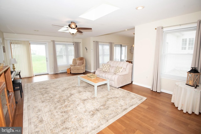 living room with hardwood / wood-style floors, ceiling fan, and a skylight