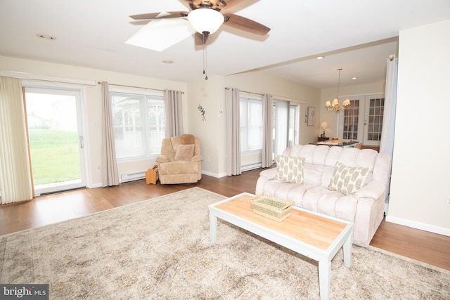 living room featuring a baseboard heating unit, ceiling fan with notable chandelier, and hardwood / wood-style flooring