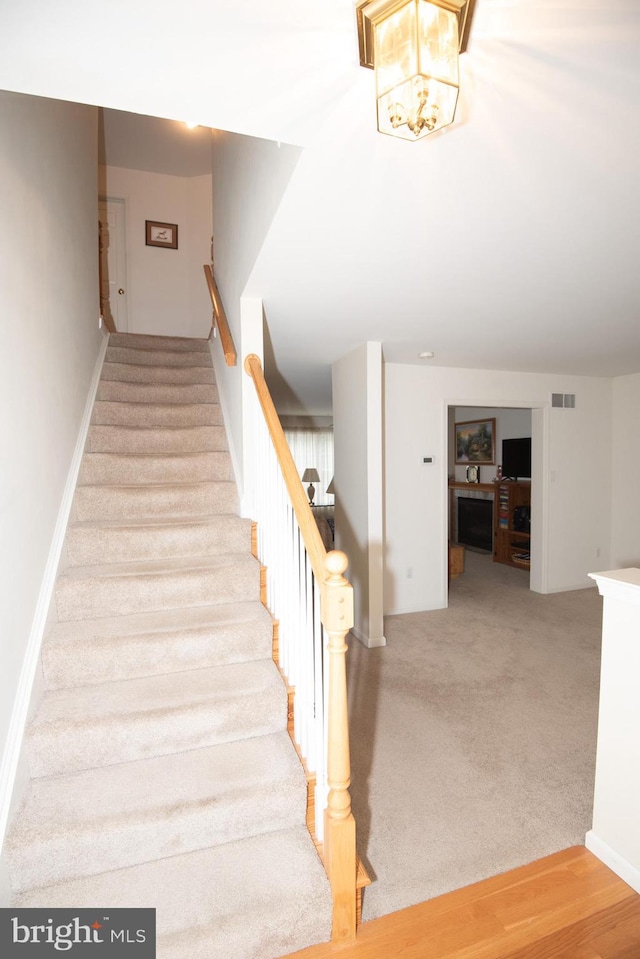 staircase featuring a chandelier and hardwood / wood-style flooring