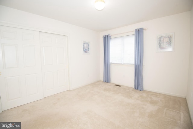 unfurnished bedroom featuring light colored carpet and a closet