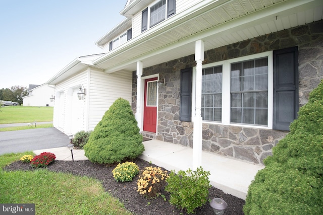 view of exterior entry featuring a porch and a garage