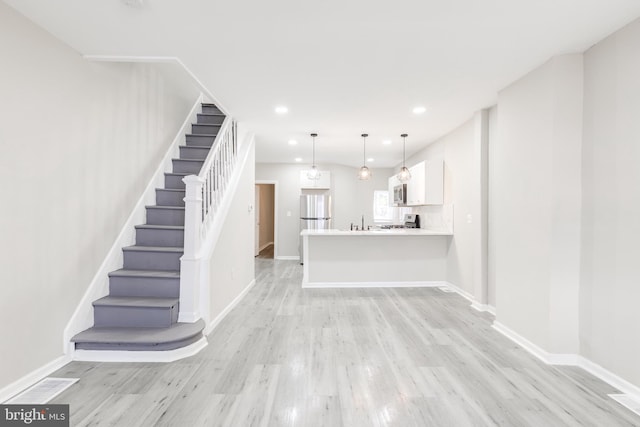 unfurnished living room featuring light hardwood / wood-style flooring and sink