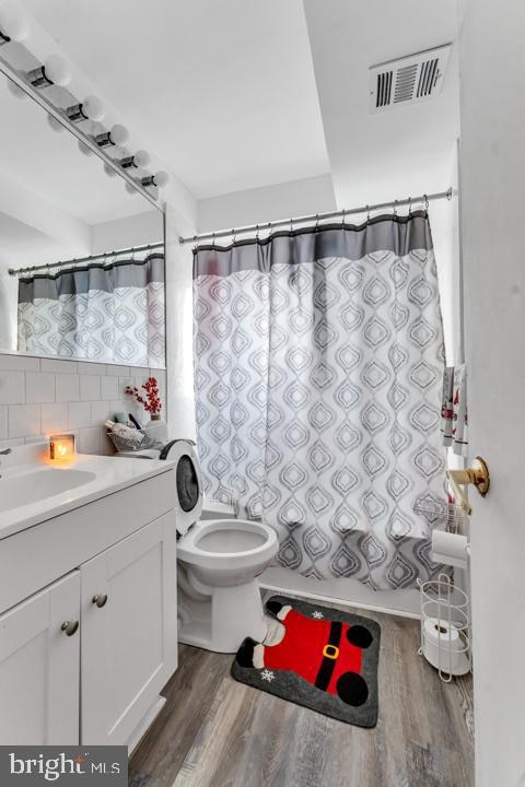 bathroom featuring hardwood / wood-style floors, decorative backsplash, toilet, and vanity