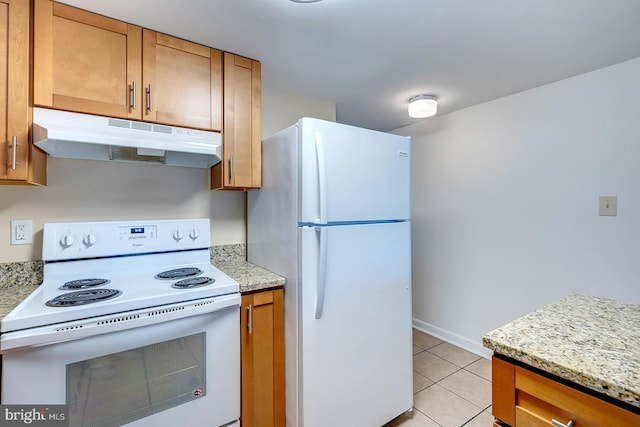 kitchen featuring light stone countertops, light tile patterned floors, and white appliances