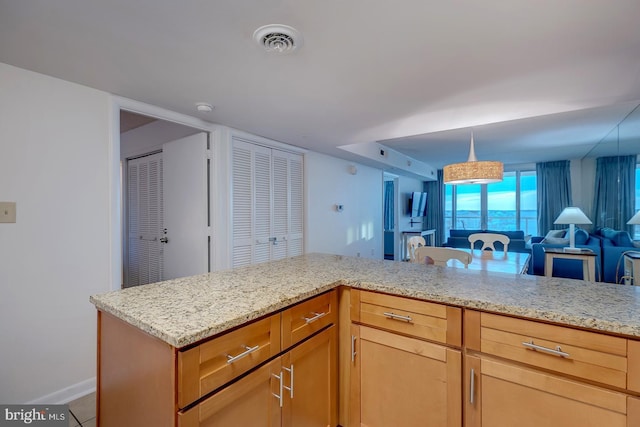 kitchen featuring light stone countertops, tile patterned flooring, and pendant lighting