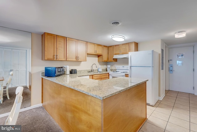 kitchen with white appliances, sink, light tile patterned floors, light stone counters, and kitchen peninsula