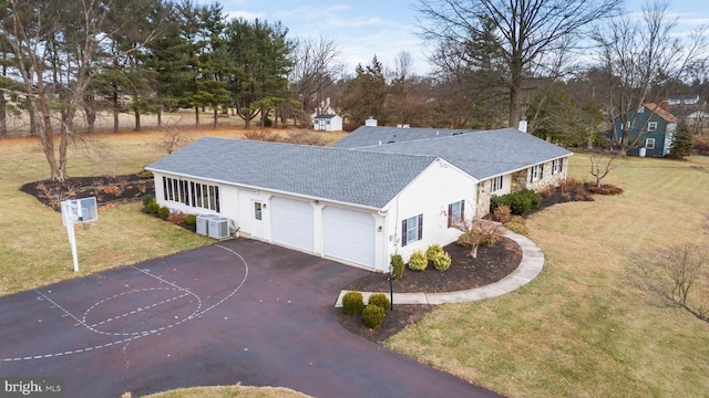 exterior space with a front yard, a garage, and cooling unit