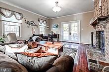 living room featuring crown molding, french doors, wood-type flooring, and a brick fireplace