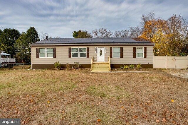 view of front facade featuring solar panels and a front lawn