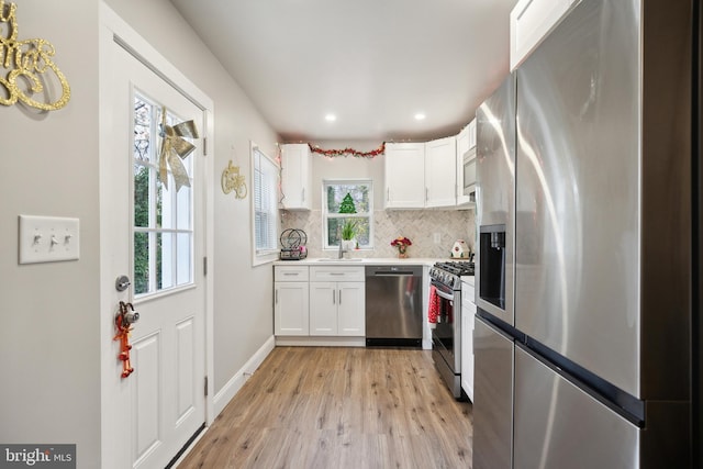 kitchen with sink, tasteful backsplash, light hardwood / wood-style floors, white cabinetry, and stainless steel appliances