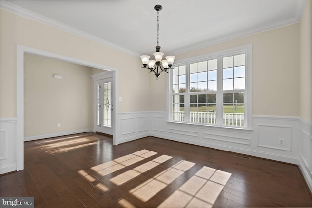 unfurnished dining area featuring ornamental molding, dark hardwood / wood-style flooring, a healthy amount of sunlight, and an inviting chandelier