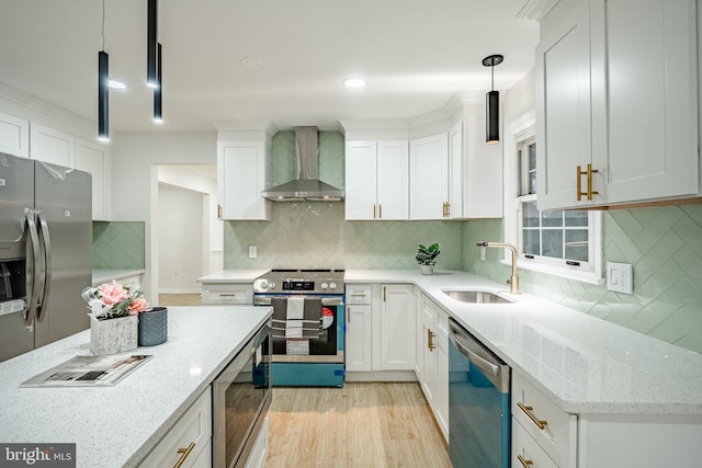 kitchen with pendant lighting, wall chimney exhaust hood, white cabinets, and stainless steel appliances