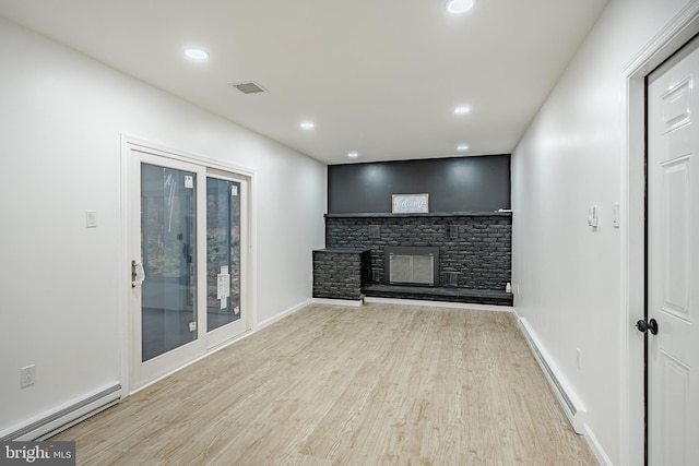 unfurnished living room with a fireplace, a baseboard radiator, and light hardwood / wood-style flooring