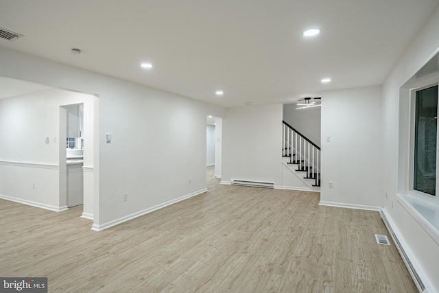 interior space featuring light hardwood / wood-style flooring, ceiling fan, and a baseboard heating unit