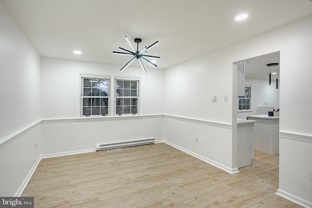 empty room with a notable chandelier, light hardwood / wood-style floors, and a baseboard radiator