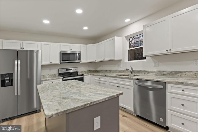 kitchen featuring light stone countertops, appliances with stainless steel finishes, light wood-type flooring, sink, and white cabinets