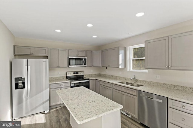 kitchen featuring light stone countertops, dark hardwood / wood-style flooring, stainless steel appliances, sink, and a kitchen island