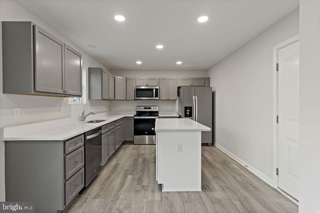 kitchen featuring gray cabinetry, a center island, stainless steel appliances, and light hardwood / wood-style flooring