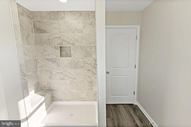 bathroom with tiled shower and hardwood / wood-style flooring