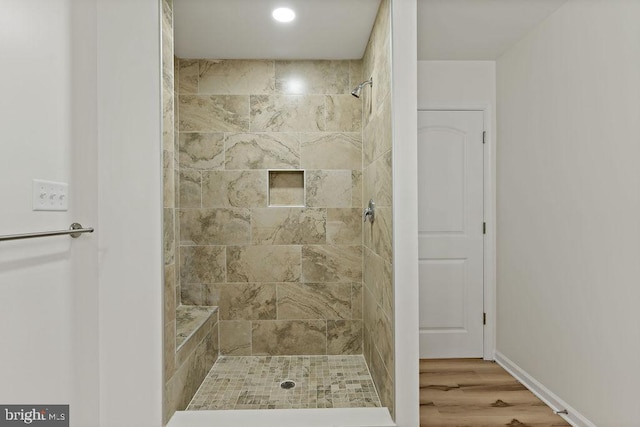 bathroom featuring a tile shower and wood-type flooring