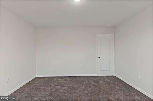 spare room with dark colored carpet