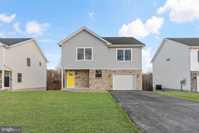 view of front of home with a garage, a front lawn, and cooling unit