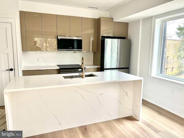 kitchen featuring gray cabinetry, sink, light hardwood / wood-style flooring, decorative backsplash, and stainless steel appliances