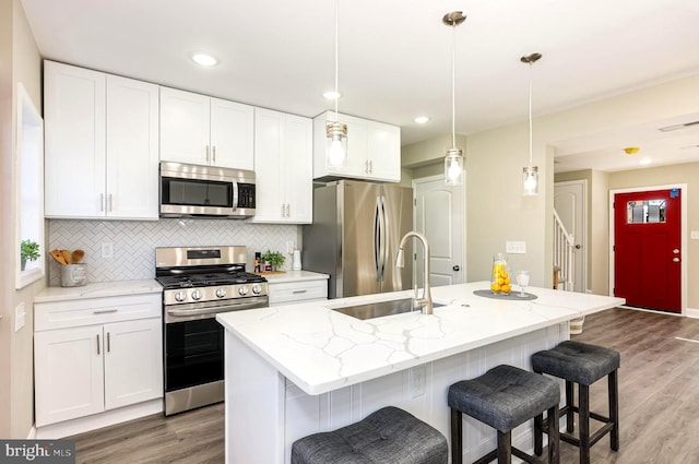 kitchen with white cabinets, sink, a kitchen island with sink, and appliances with stainless steel finishes