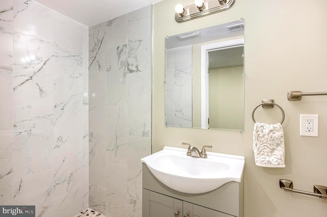 bathroom with a tile shower and vanity